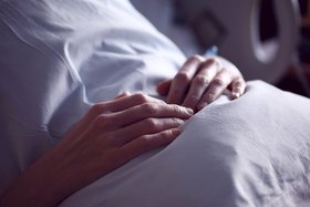 Hände auf einem Kissen in einem Krankenhausbett